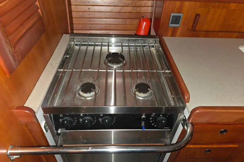 Slide: The Image of Galley stove in 2000 J Boats J/46 yacht, featuring three burners and wooden cabinetry. - 63