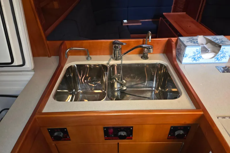 Slide: The Image of Galley sink in 2000 J Boats J/46 yacht, featuring dual faucets and wooden cabinetry. - 66