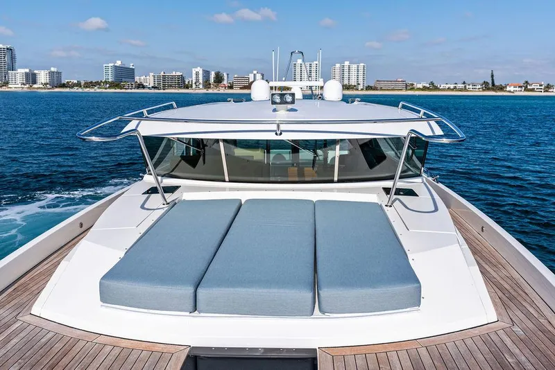 Slide: The Image of 2018 Delta Powerboats 54 IPS yacht with sunbathing deck, cruising near a city skyline. - 25