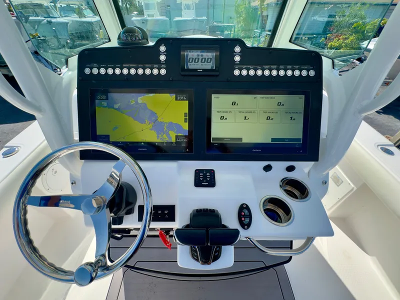 Slide: The Image of 2023 Everglades 273 Center Console boat dashboard with dual navigation screens and steering wheel. - 24