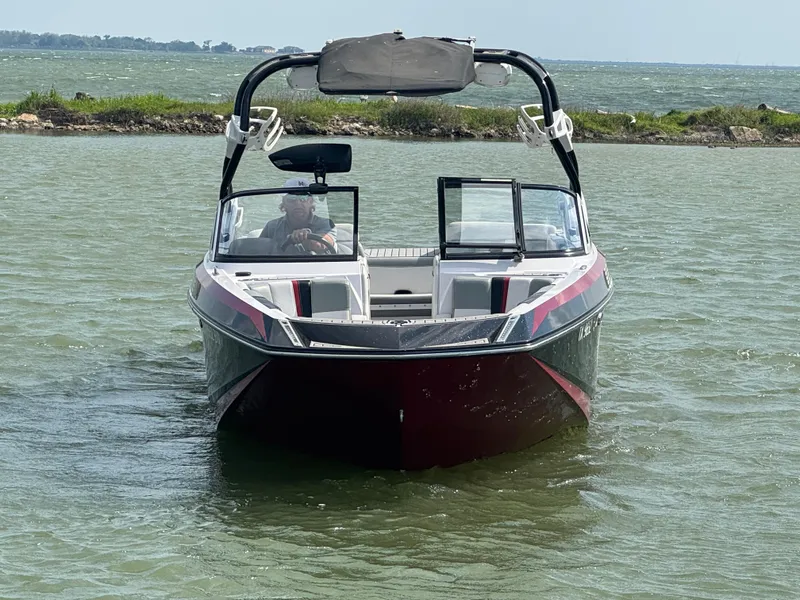 Slide: The Image of 2013 Nautique Super Air Nautique G25 boat on water, front view, with open bow design. - 3