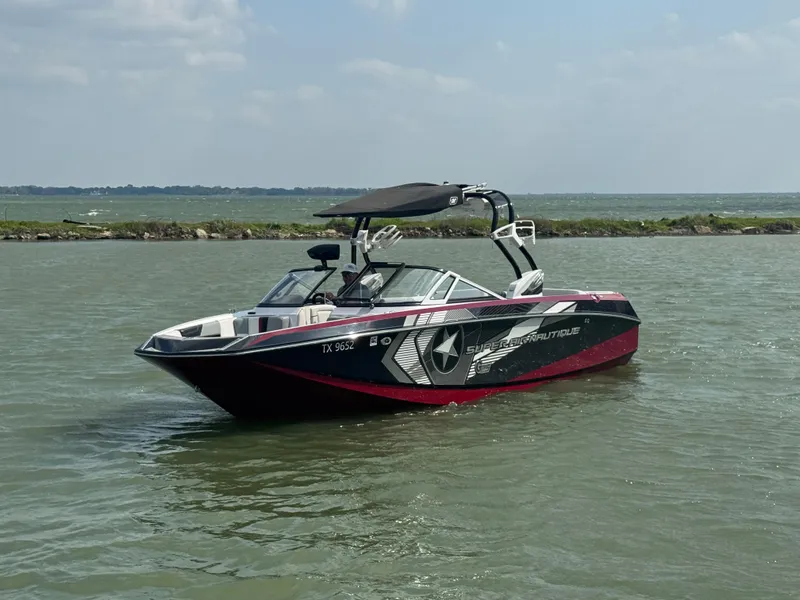 Slide: The Image of 2013 Nautique Super Air Nautique G25 boat on calm water, featuring sleek design and graphics. - 4