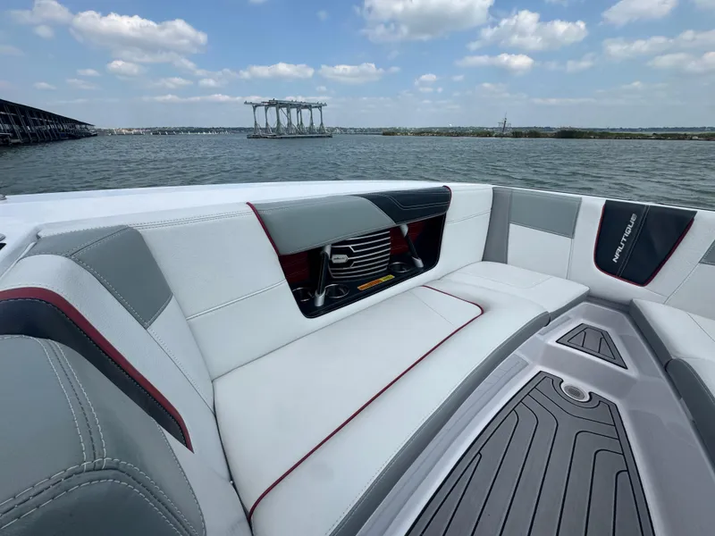Slide: The Image of 2013 Nautique Super Air Nautique G25 boat interior with gray and white seating on a lake. - 7