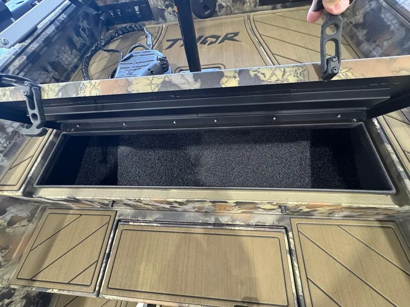 Slide: The Image of Open storage compartment in 2025 Thor TIMBER HAMMER boat, featuring camouflage design. - 11