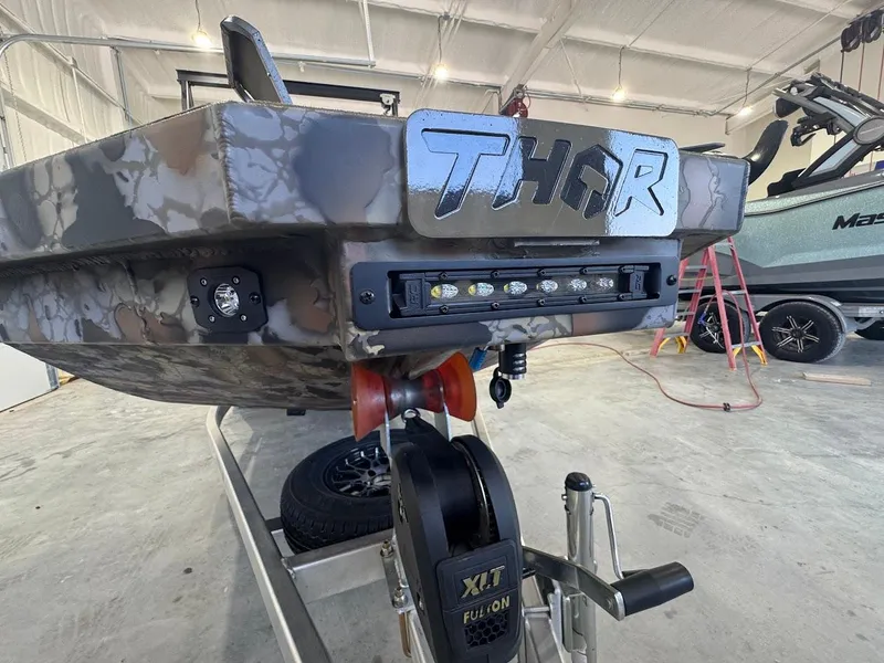 Slide: The Image of Thor TIMBER HAMMER 2025 boat with camouflage design in a garage setting. - 14