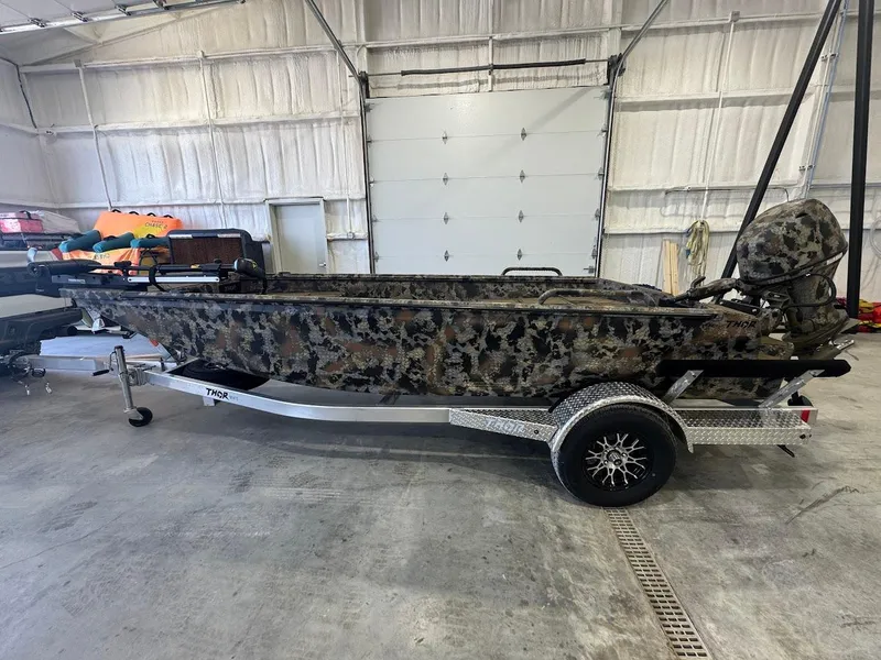 Slide: The Image of Camouflage-patterned Thor TIMBER HAMMER boat, 2025 model, on a trailer in a garage. - 2