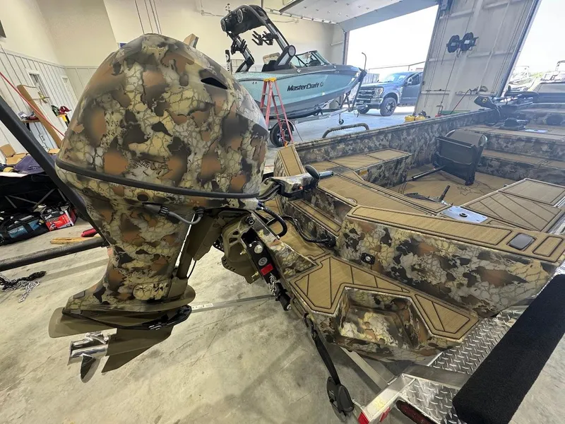 Slide: The Image of Camouflage-patterned Thor TIMBER HAMMER 2025 boat motor in a garage setting. - 4