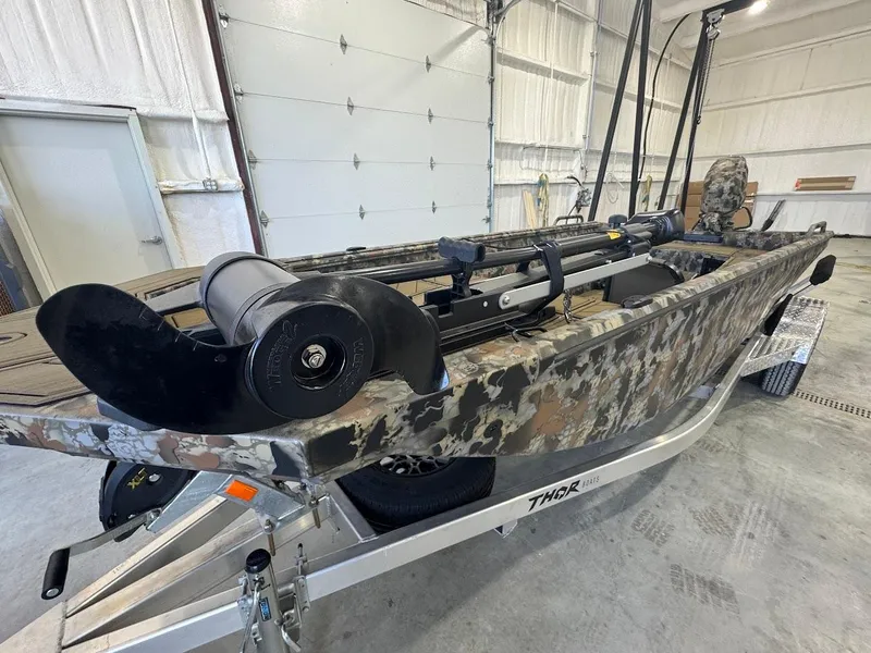 Slide: The Image of 2025 Thor TIMBER HAMMER boat with camouflage design in a garage setting. - 6
