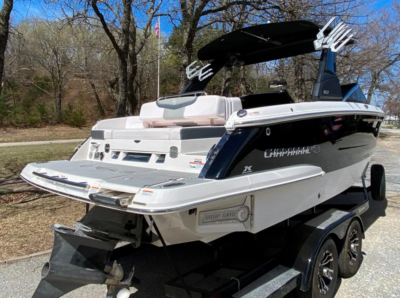 Slide: The Image of 2020 Chaparral 25 SURF boat on trailer, parked outdoors with trees in background. - 2