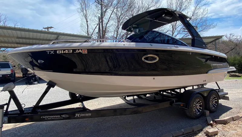 Slide: The Image of 2020 Chaparral 25 SURF boat on trailer, black and white design, parked outdoors. - 4