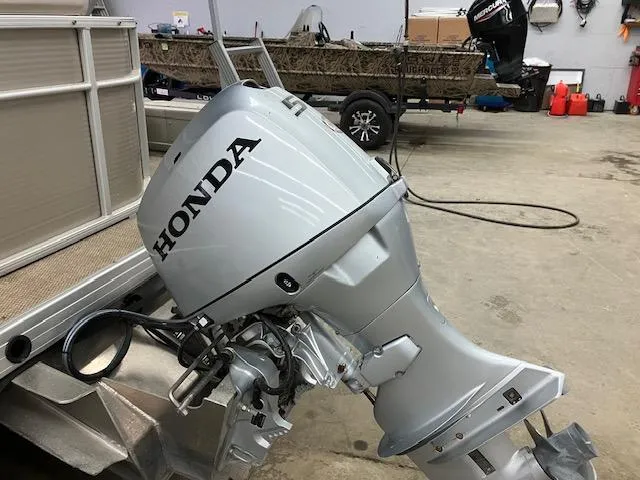 Slide: The Image of Honda outboard motor on a 2017 Godfrey Sweetwater 2286 C pontoon boat in a garage. - 12