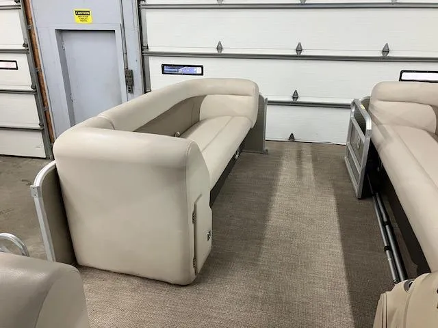 Slide: The Image of 2017 Godfrey Sweetwater 2286 C pontoon boat interior with beige seating in a garage. - 7