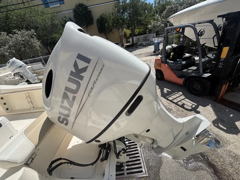 Slide: The Image of 2025 Bulls Bay 200 Center Console with Suzuki outboard motor, parked near forklift. - 19