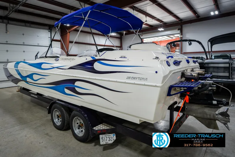 Slide: The Image of 2001 Eliminator 26 Daytona boat with blue flame design on trailer in a garage. - 10