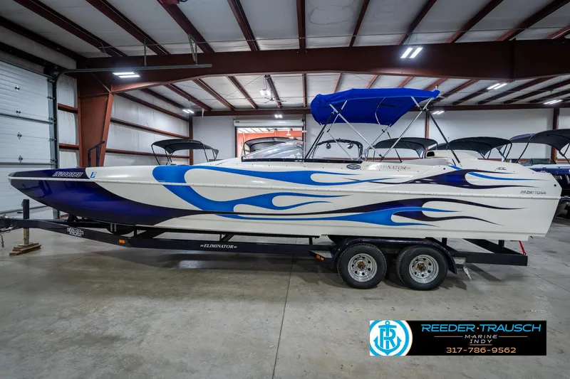 Slide: The Image of 2001 Eliminator 26 Daytona boat with blue flame design in a warehouse. - 11