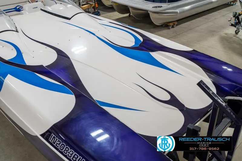 Slide: The Image of 2001 Eliminator 26 Daytona boat with blue and purple flame design in a showroom. - 13