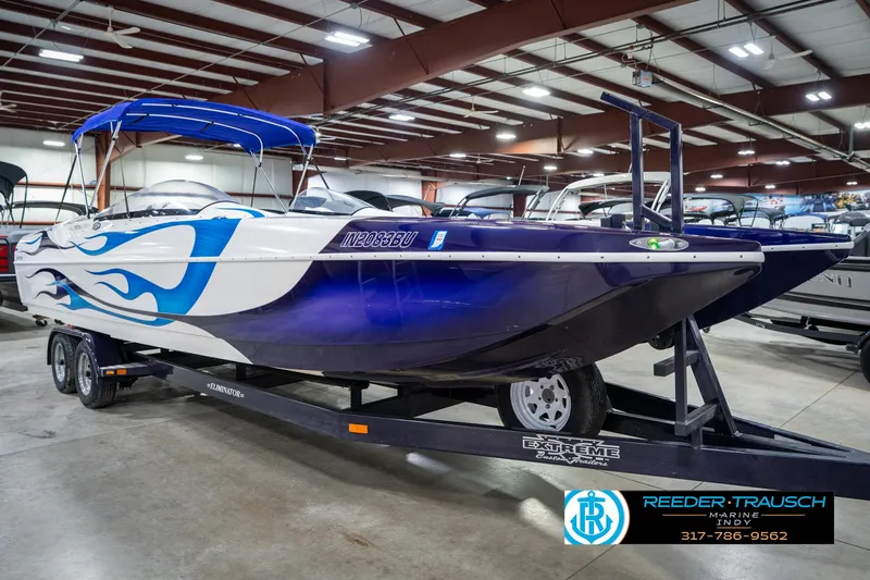 Slide: The Image of 2001 Eliminator 26 Daytona boat with blue flame design on trailer in showroom. - 6
