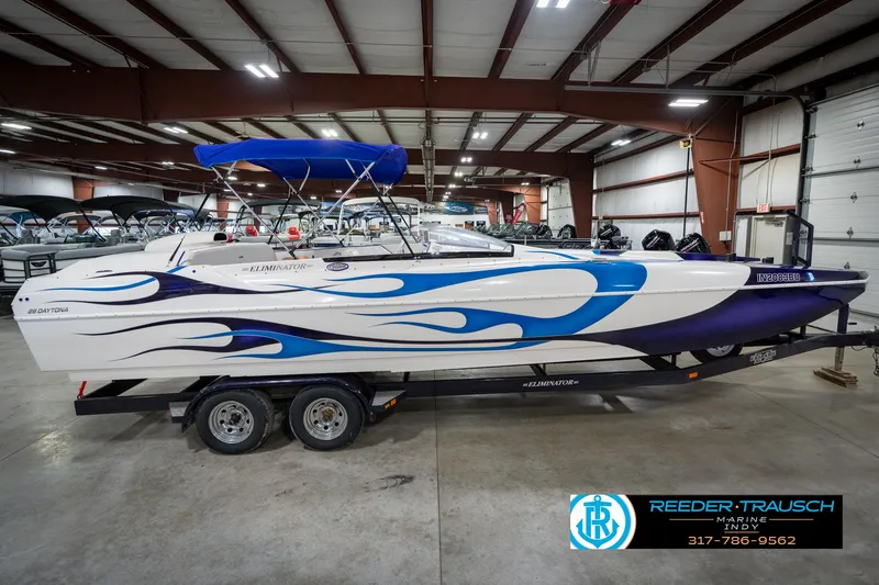 Slide: The Image of 2001 Eliminator 26 Daytona boat with blue flame design in indoor showroom. - 7