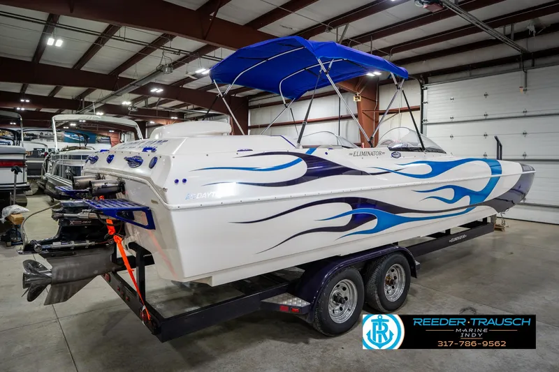 Slide: The Image of 2001 Eliminator 26 Daytona boat with blue flame design in a showroom. - 8