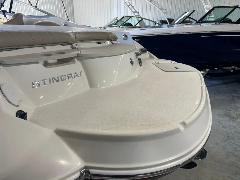 Slide: The Image of 2015 Stingray 215 LR boat in showroom, featuring spacious deck and sleek design. - 5