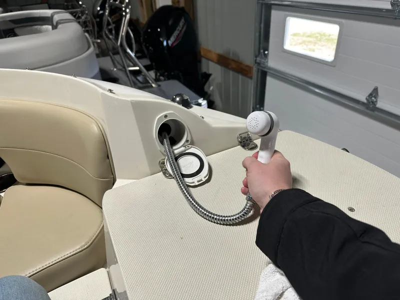 Slide: The Image of Person holding a showerhead on a 2015 Stingray 215 LR boat's deck. - 8
