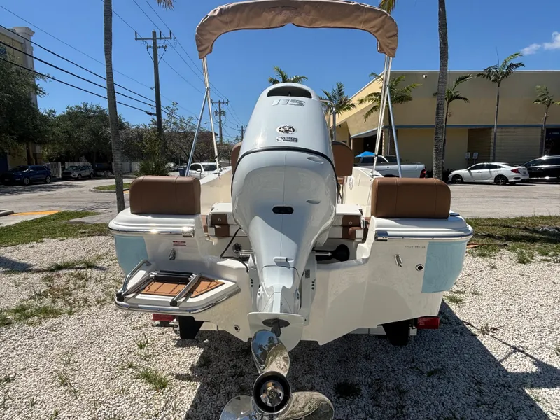 Slide: The Image of 2025 Pioneer 180 Islander boat with outboard motor, parked on gravel under a clear blue sky. - 6