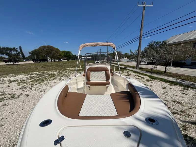Slide: The Image of 2025 Pioneer 180 Islander boat with tan seating, parked outdoors on gravel. - 8
