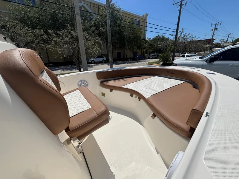 Slide: The Image of 2025 Pioneer 180 Islander boat interior with brown and white seating, parked outdoors. - 9
