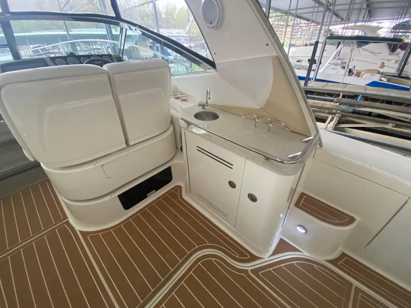 Slide: The Image of 2009 Sea Ray 350 Sundancer interior with kitchenette and seating, featuring wood-patterned flooring. - 14