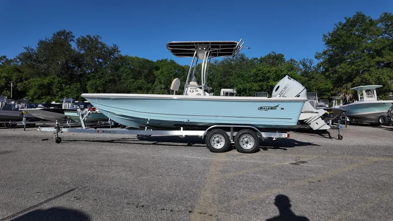 Slide: The Image of 2025 Bulls Bay 2200XS boat on trailer in parking lot, surrounded by trees and other boats. - 12