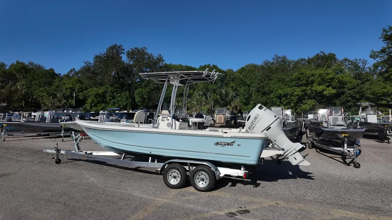 Slide: The Image of 2025 Bulls Bay 2200XS boat on trailer, parked outdoors with trees in background. - 16