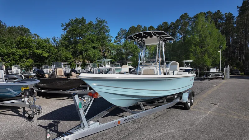 Slide: The Image of 2025 Bulls Bay 2200XS boat on trailer, parked outdoors with trees in the background. - 2