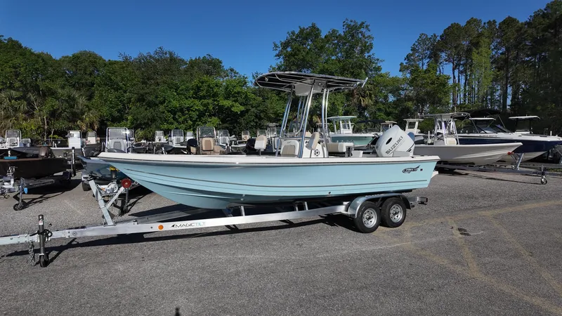 Slide: The Image of 2025 Bulls Bay 2200XS boat on trailer in outdoor lot, surrounded by trees and other boats. - 7