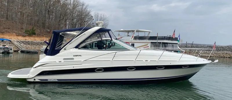 Slide: The Image of 2004 Doral Boca Grande 36 yacht on calm water, overcast sky, docked near shoreline. - 0