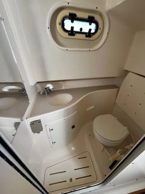 Slide: The Image of 2003 Pursuit 2870 Walkaround boat bathroom with sink, toilet, and porthole window. - 15