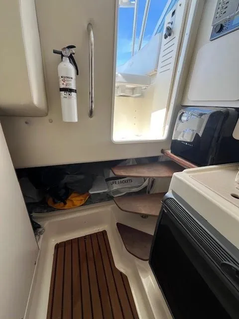 Slide: The Image of 2003 Pursuit 2870 Walkaround cabin interior with fire extinguisher and wooden flooring. - 19