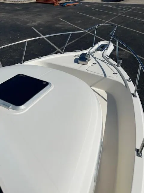 Slide: The Image of 2003 Pursuit 2870 Walkaround boat deck with railing and hatch, parked on asphalt. - 21