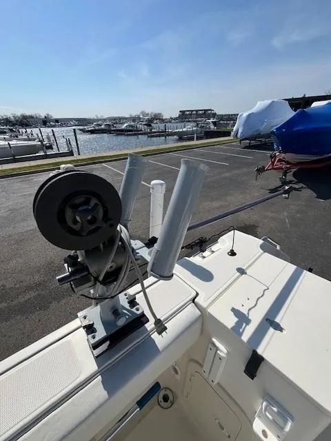 Slide: The Image of 2003 Pursuit 2870 Walkaround boat with fishing rod holders, docked near a marina. - 24