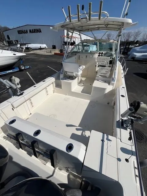 Slide: The Image of 2003 Pursuit 2870 Walkaround boat at a marina, featuring spacious deck and fishing rod holders. - 6