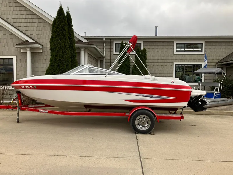 Slide: The Image of 2011 Glastron GT 205 boat on trailer, red and white design, parked outside a building. - 3