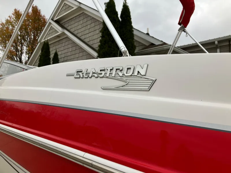 Slide: The Image of 2011 Glastron GT 205 boat with red and white exterior, parked near a house. - 4