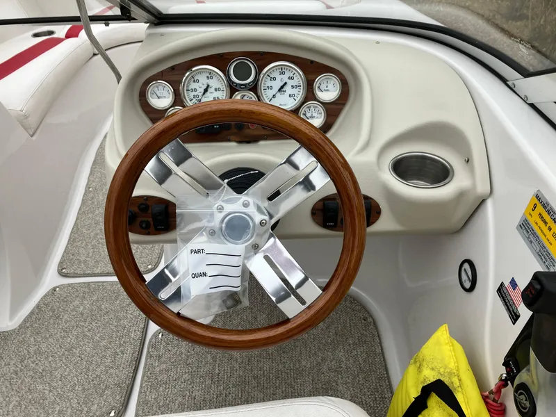 Slide: The Image of Steering wheel and dashboard of a 2011 Glastron GT 205 boat, featuring wood accents. - 9