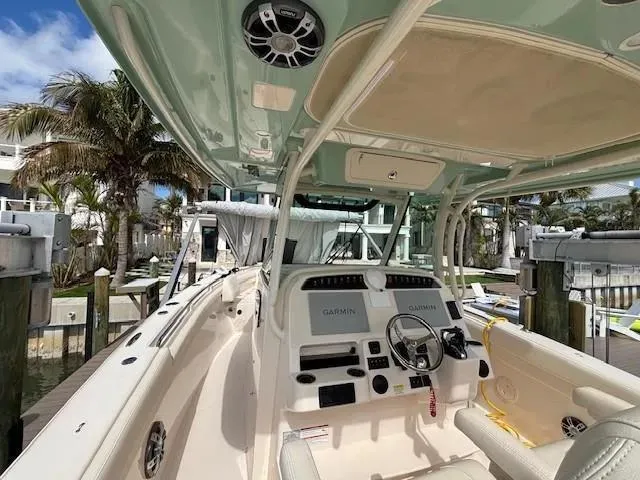 Slide: The Image of 2024 Grady-White Canyon 336 boat interior with helm, docked near palm trees. - 8