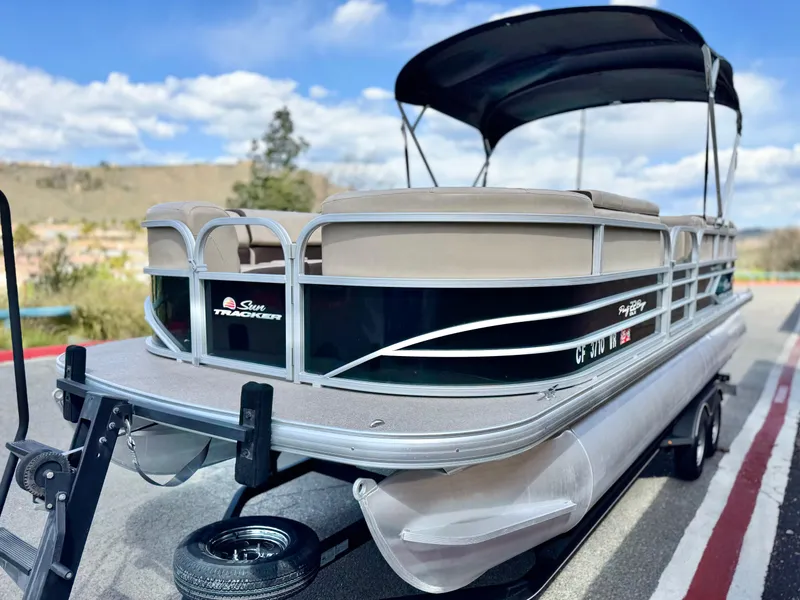 Slide: The Image of 2018 Sun Tracker Party Barge 22 DLX pontoon boat on trailer, under blue sky. - 4