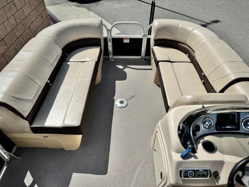 Slide: The Image of 2018 Sun Tracker Party Barge 22 DLX interior with beige seating and control console. - 9