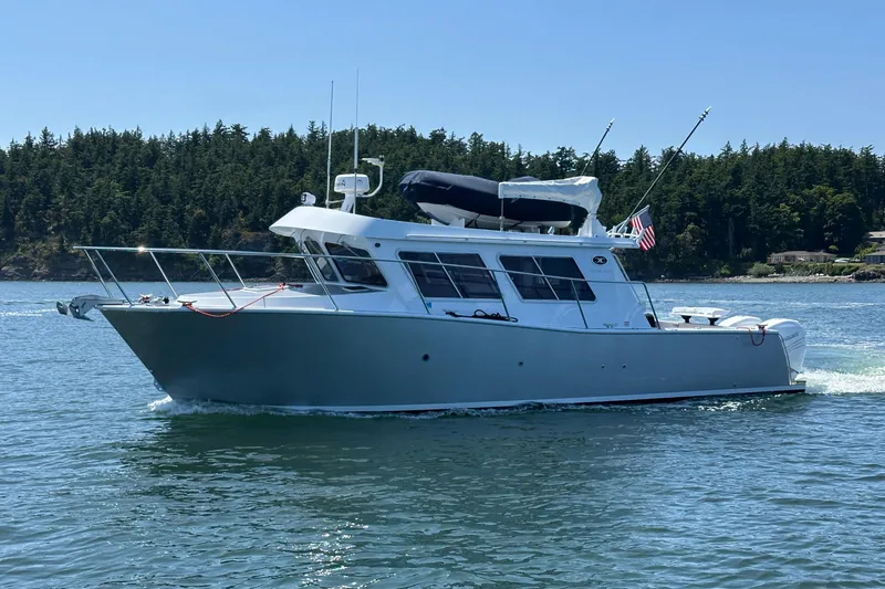 Slide: The Image of 2020 Coastal Craft 33 ProFish boat cruising on a serene lake with forested shoreline. - 2