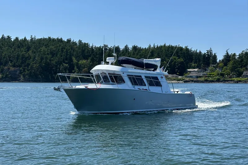 Slide: The Image of 2020 Coastal Craft 33 ProFish boat cruising on a serene lake with forested shoreline. - 3