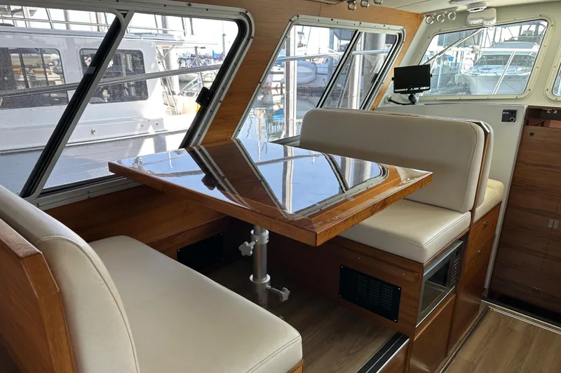 Slide: The Image of 2020 Coastal Craft 33 ProFish interior with dining area, wooden table, and cushioned seating. - 30