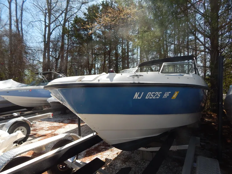 Slide: The Image of 2013 Bayliner 235 Bowrider boat on trailer, surrounded by trees. - 2