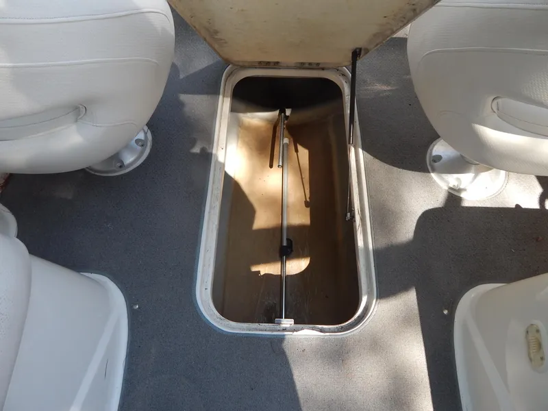 Slide: The Image of 2013 Bayliner 235 Bowrider storage compartment between white seats. - 27